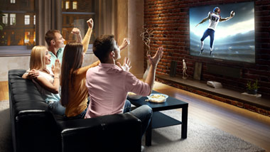Sports fans sitting on couch watching football